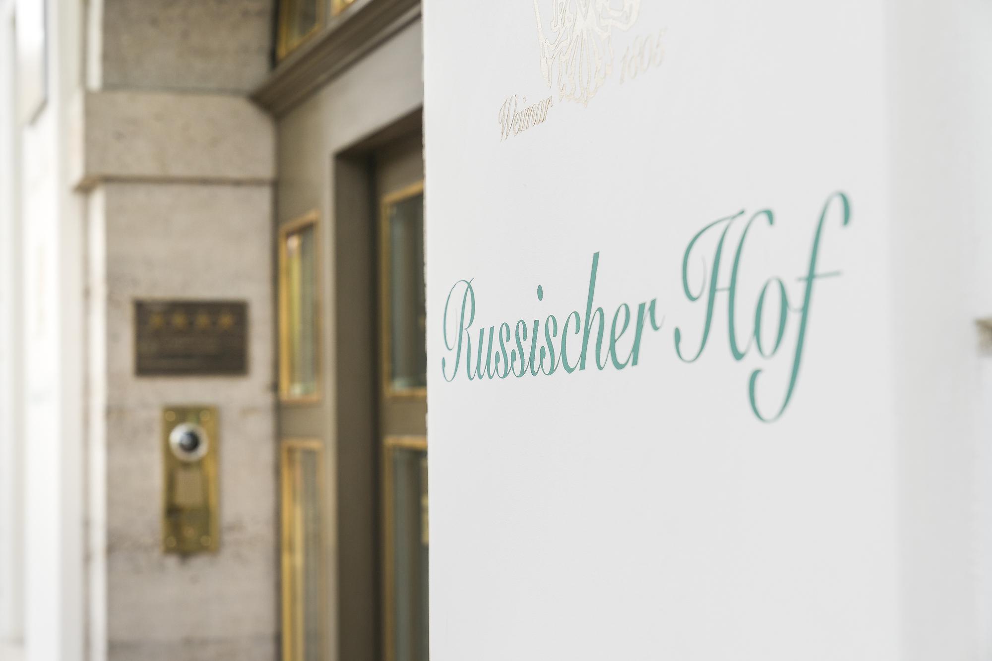 Eingang des Hotels Russischer Hof in Weimar mit Glastür, Messingschild und grüner Schrift auf weißer Fassade